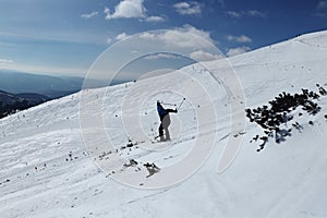 Lyžař oblečený v černé a modré. Free rider jumping na horském svahu na pozadí nádherného Chopku, Nízké Tatry v