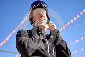 Skier Fastening Helmet Against Blue Sky