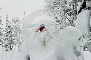 Skier freerider jumping from a snow ramp in the sun on a background of forest and mountains