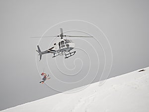 Skier freerider jumps from helicopter heliski on a snowy mountain photo