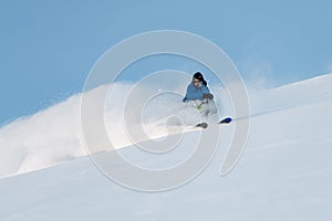 Skier is freeriding, downhill skiing, with powder rising up