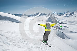 A skier in full sports equipment jumps into the abyss from the top of the glacier against the background of the blue sky