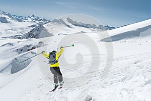 A skier in full sports equipment jumps into the abyss from the top of the glacier against the background of the blue sky