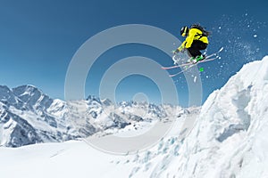 A skier in full sports equipment jumps into the precipice from the top of the glacier against the background of the blue