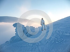 Skier girl in blue jumpsuit on blue slope near the icy snowdrift. Mountain winter landscape in the Carpathians in Ukraine