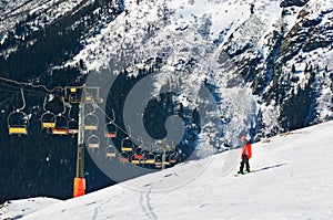 Skier going down the slope under ski lift. Cable car in mountains