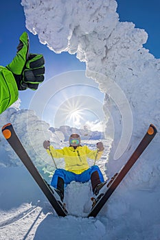 Skier is having fun during beautiful winter scenery in high mountains with thumbs up against sunset