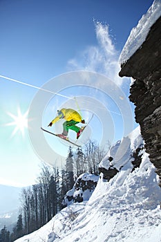 Skier jumping against blue sky from the rock