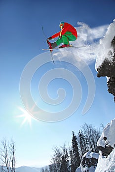 Skier jumping against blue sky from the rock