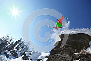 Skier jumping against blue sky from the rock