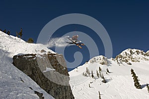 Skier jumping cross tips off cliff