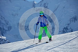 Skier kid in colorful gear and goggles enjoys the alpine chill