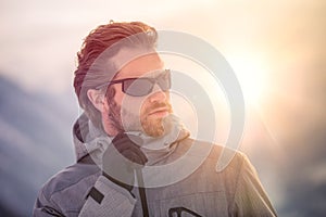Skier man detail wearing anorak jacket with sunglasses portrait. exploring snowy land walking and skiing with alpine ski photo