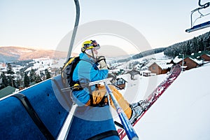 Skier man sitting at ski chair lift in beautiful day