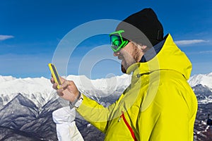 Skier man texting with cell phone over mountain