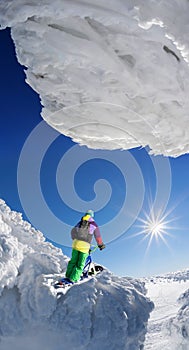 Skier on monoski in high mountains against blue sky