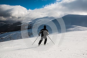 Skier in mountains, prepared piste and sunny day