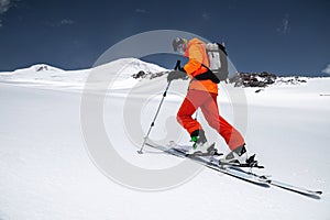 A skier in an orange suit skis in a mountain off-piste skiing in the northern caucasus of Mount Elbrus