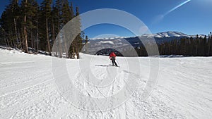 Skier in red jacket going downhill on a high speed