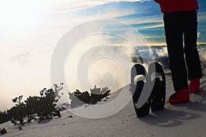 Skier in red winter jacket with fun snowshoes stay in snow in mountains.