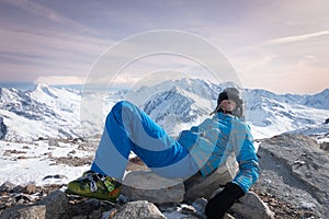Skier relaxing, resting, laying on rocks, at sunny day on winter season with beautiful rose sky