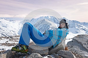 Skier relaxing, resting, laying on rocks, at sunny day on winter season with beautiful rose sky