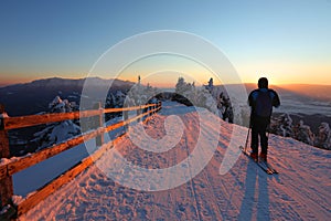 A skier is resting at a ski resort with beautiful view to the snowy mountains.