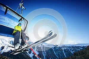 Skier siting on ski-lift - lift at sunny day and mountain