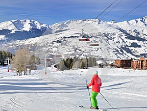 Skier on ski slopes in french alps resort and chair lift