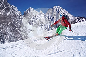 Skier skiing downhill in high mountains