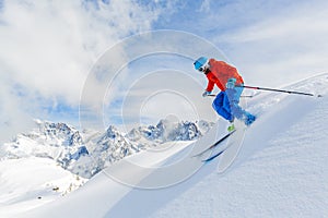 Skier skiing downhill in high mountains.