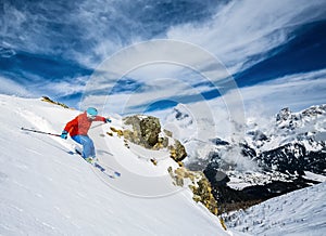 Skier skiing downhill in high mountains.