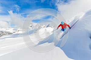 Skier skiing downhill in high mountains.