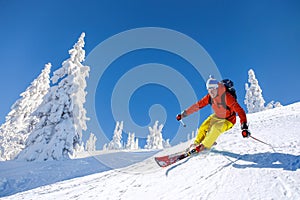 Skier skiing downhill in high mountains against blue sky