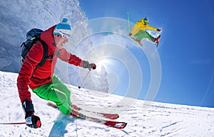 Skier skiing downhill in high mountains against blue sky