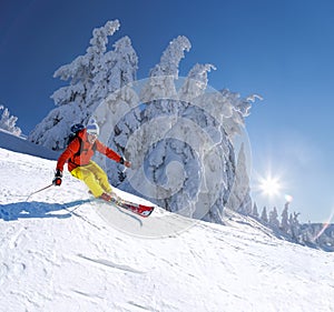 Skier skiing downhill in high mountains against blue sky