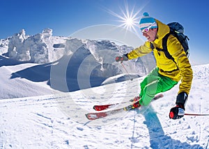 Skier skiing downhill in high mountains against blue sky