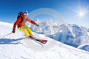 Skier skiing downhill in high mountains against blue sky