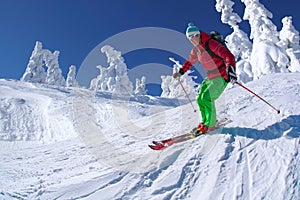 Skier skiing downhill in high mountains against blue sky