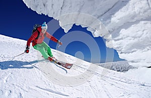 Skier skiing downhill in high mountains against cable lift