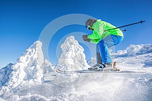 Skier skiing downhill in high mountains against against the fairytale winter forest