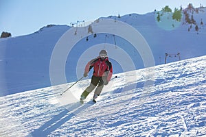 Skier skiing downhill in high mountains against sunset