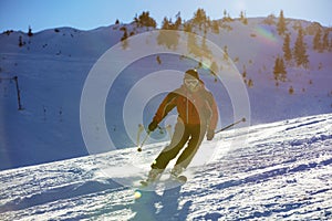 Skier skiing downhill in high mountains against sunset