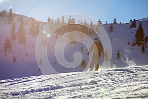 Skier skiing downhill in high mountains against sunset