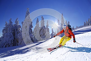 Skier skiing downhill in high mountains against sunset