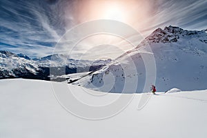 Skier skiing downhill in high mountains against sunset