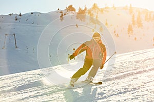 Skier skiing downhill in high mountains against sunset