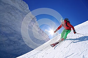 Skier skiing downhill in high mountains against sunset