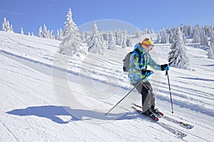 Skier skiing downhill on ski slope