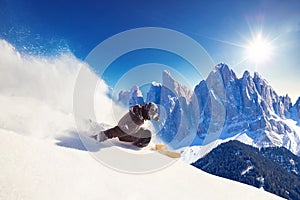 Skier skiing downhill during sunny day in Alps mountains and forest. Extreme winter sports